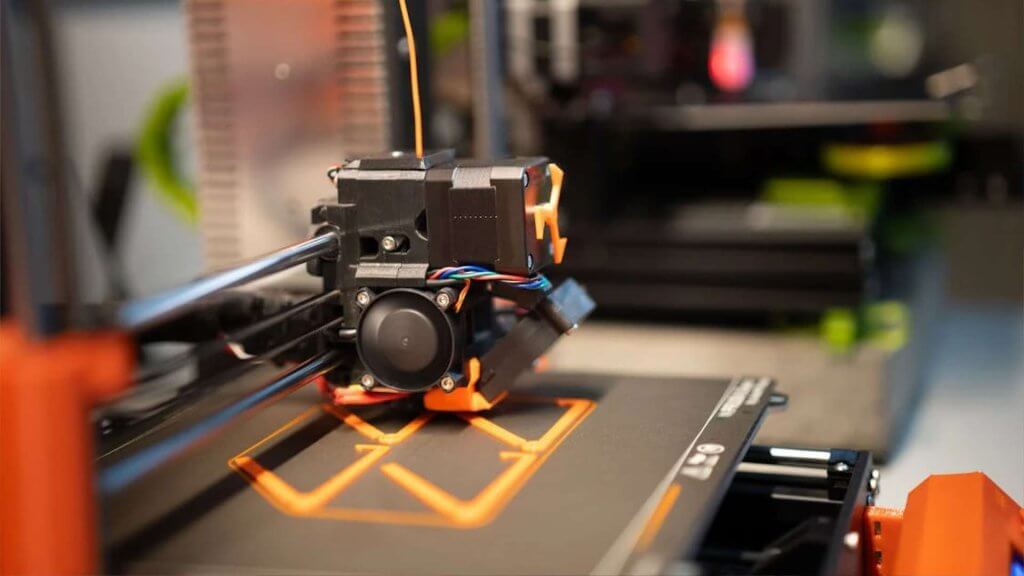 Een close-up van een 3D-printer die een oranje object print.